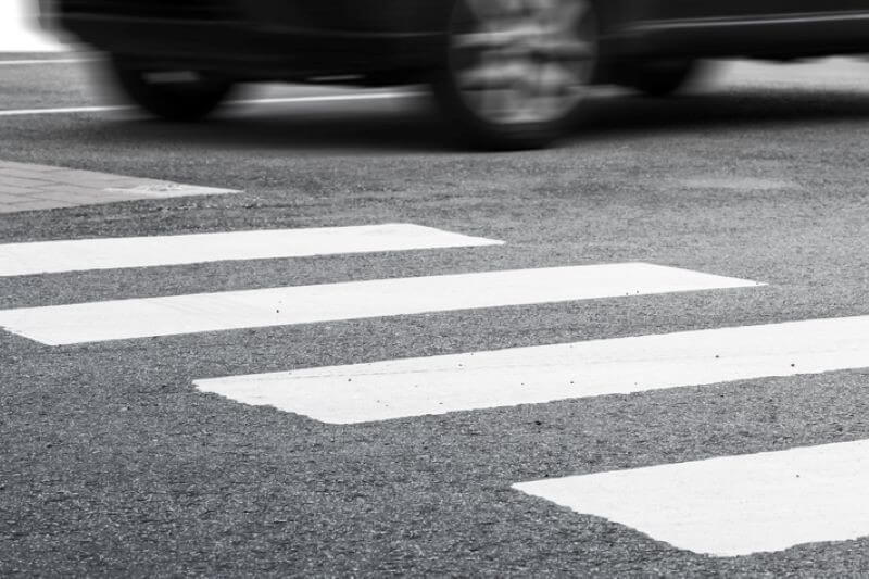 a marked pedestrian crossing with a blurry car driving past